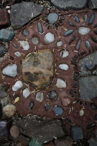 My wonderful neighbors brought the large center stone back from a trip out east where it sat in a stream that ran below a wooden covered bridge.  It is now at the entrance of the Secret Garden.  Surrounding it are Petoskey Stones that I picked up on a beach in Leland, Michigan.